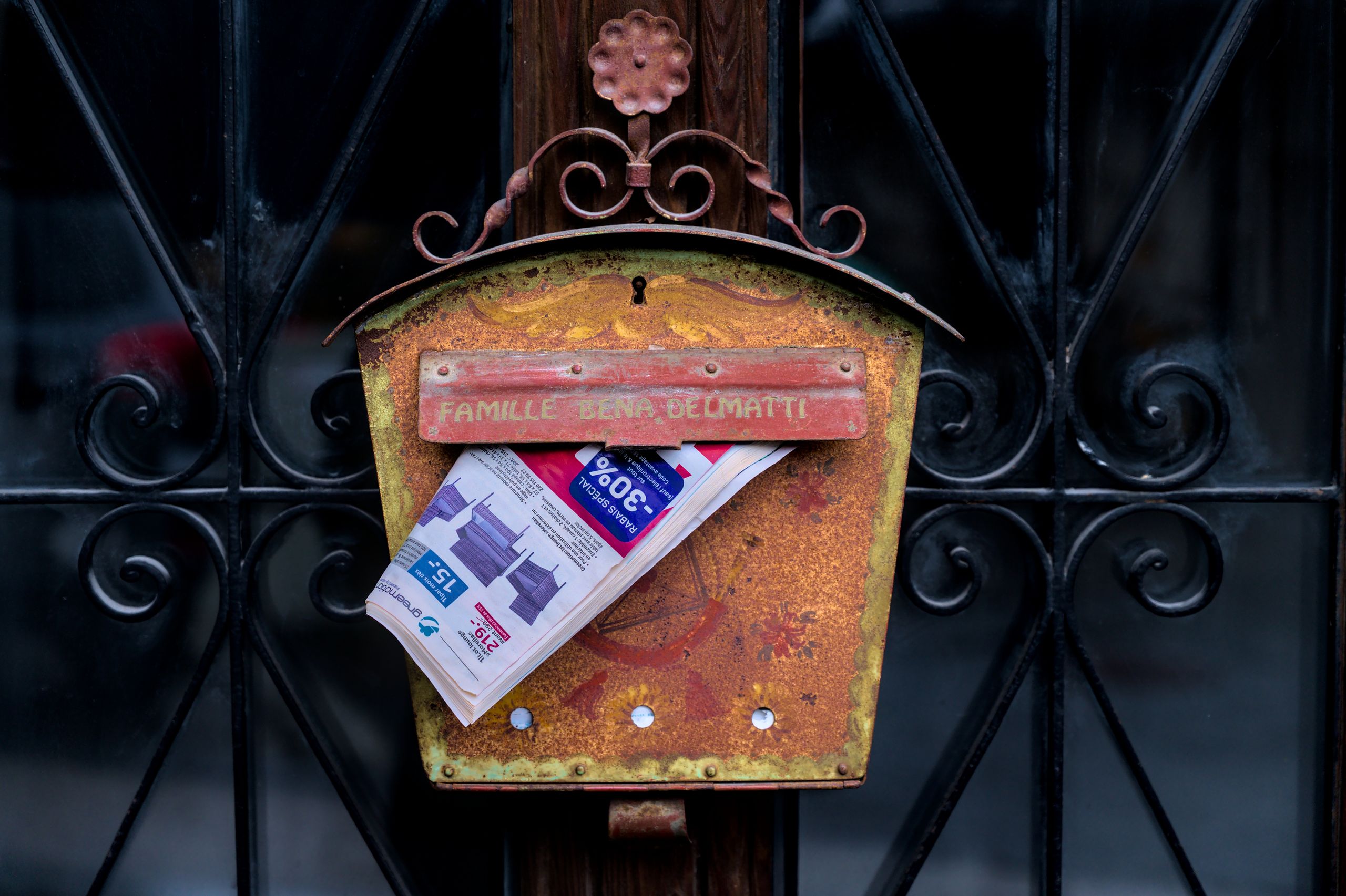 Rustic rusted mailbox holding a newspaper in Saillon, Switzerland.